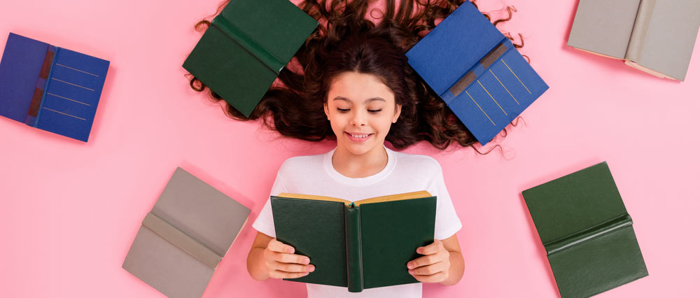 young girl reading surrounded by books
