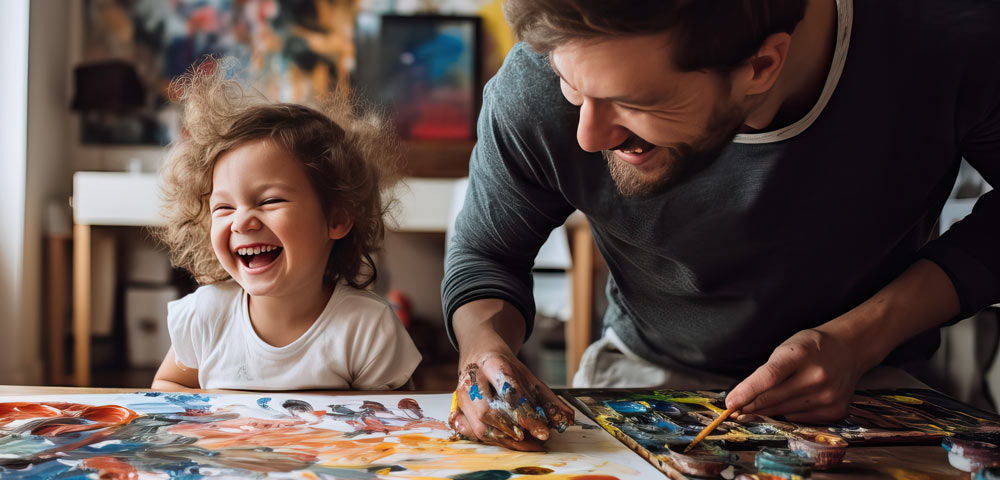 young girl laughing with father while painting and enjoying crafts