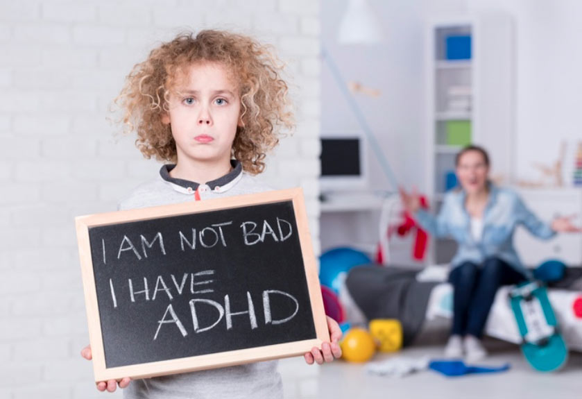 Boy holding chalkboard up saying I am not bad, I just have adhd