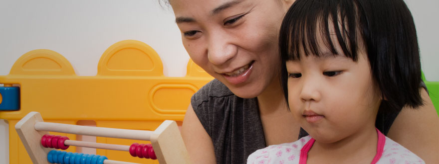 Very young girl with female teacher on an abacus