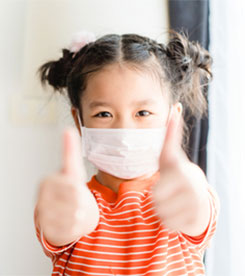 Little girl with mask on and thumbs up