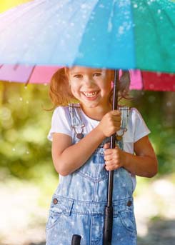 Smiling girl in the rain with an umbrella