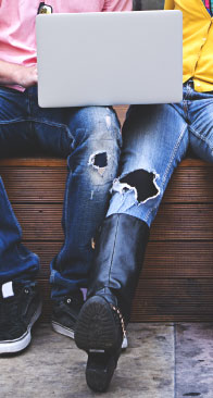 Kids sitting on a bench looking at a laptop