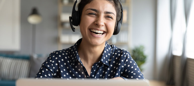 Woman smiling on a laptop with headphones on