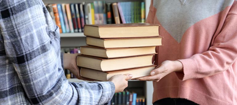 Person handing over some books to study