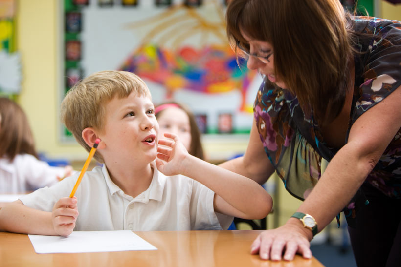 Female teacher helping a boy at his desk
