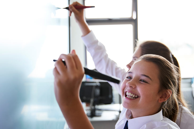 Two girls writing on a whiteboard
