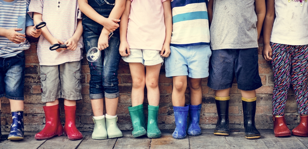 children in a stand together in a row wearing colourful wellies